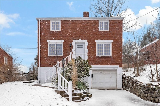 colonial house featuring a garage, stairway, brick siding, and a chimney