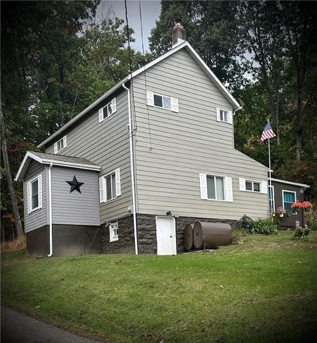 rear view of property with a yard, a chimney, and heating fuel