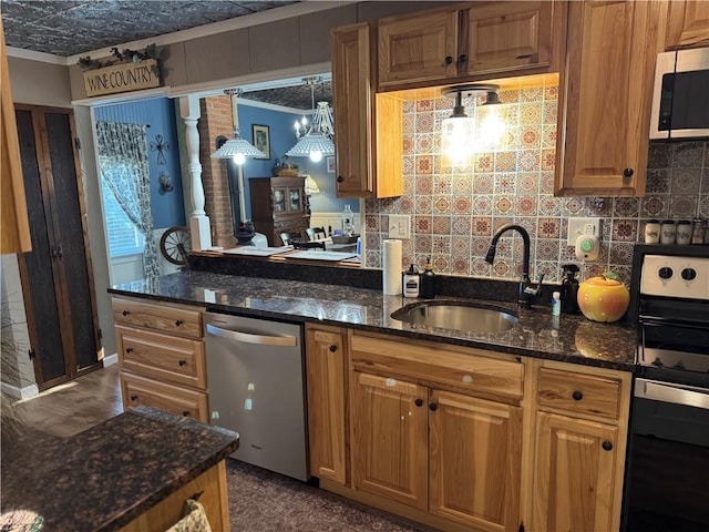 kitchen featuring appliances with stainless steel finishes, a sink, dark stone countertops, and tasteful backsplash