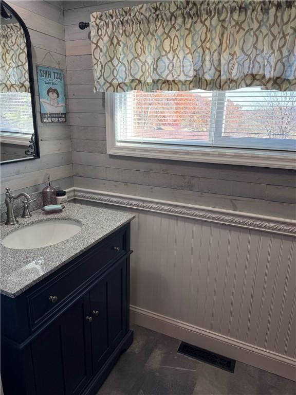 bathroom with wood walls, vanity, and visible vents