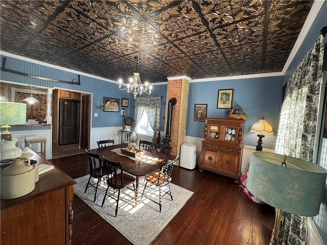 dining space featuring hardwood / wood-style flooring, ornamental molding, wainscoting, an ornate ceiling, and an inviting chandelier