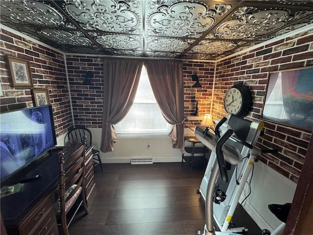 workout room with an ornate ceiling, visible vents, and brick wall