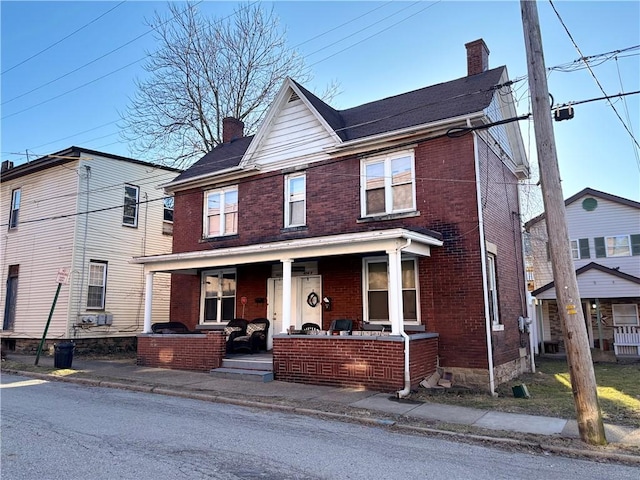 view of front of property featuring covered porch, brick siding, and a chimney