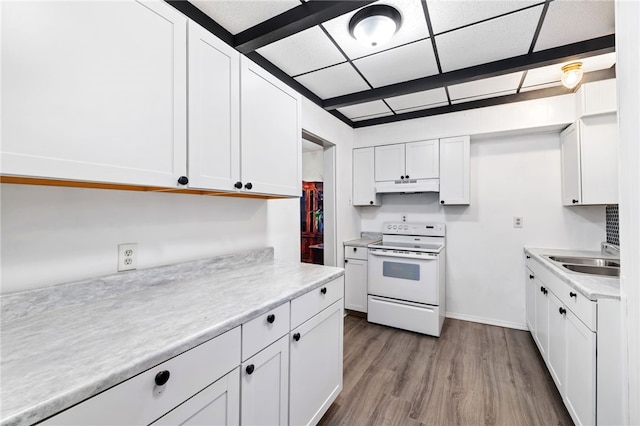 kitchen with under cabinet range hood, wood finished floors, a sink, light countertops, and white range with electric cooktop