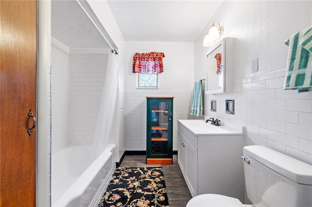 full bath with shower / tub combo, toilet, wood finished floors, vanity, and tile walls