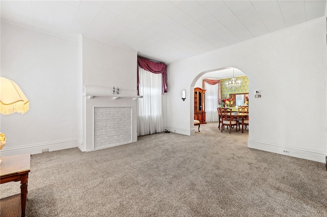 unfurnished living room featuring arched walkways, baseboards, and carpet