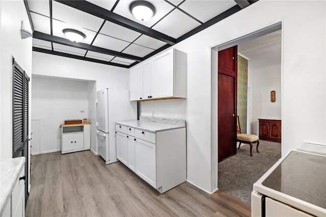 kitchen featuring light countertops, light wood-style floors, white cabinets, white appliances, and a drop ceiling