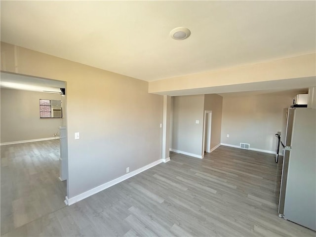 empty room with light wood finished floors, baseboards, and visible vents