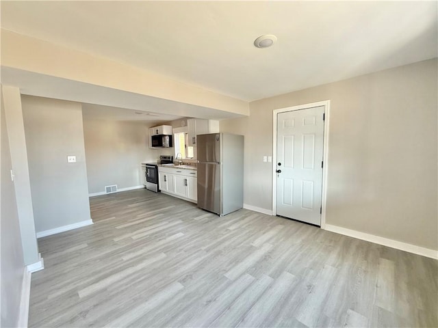 kitchen with visible vents, light wood-style flooring, appliances with stainless steel finishes, white cabinetry, and a sink