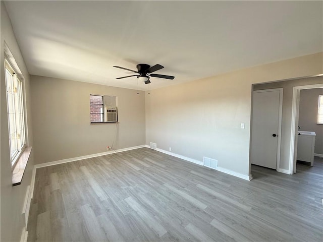 spare room featuring baseboards, wood finished floors, visible vents, and a healthy amount of sunlight