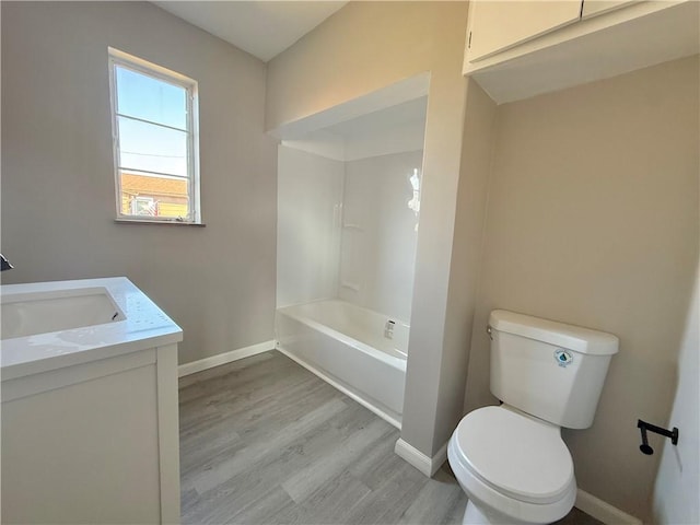 bathroom with vanity, wood finished floors, toilet, and baseboards