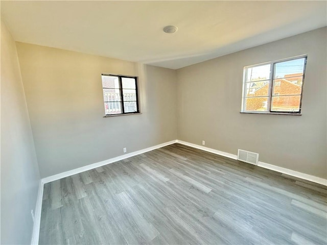 unfurnished room featuring a wealth of natural light, visible vents, and baseboards