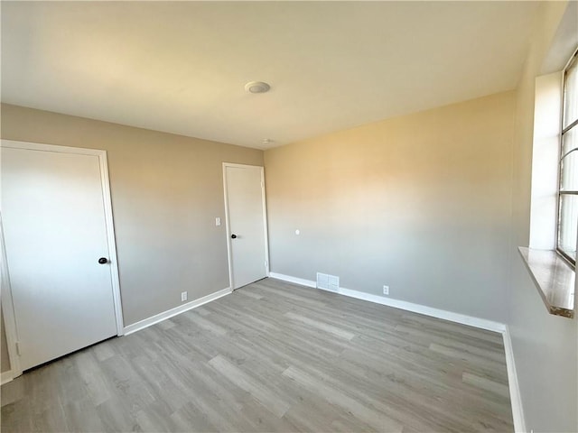 unfurnished bedroom with wood finished floors, visible vents, and baseboards