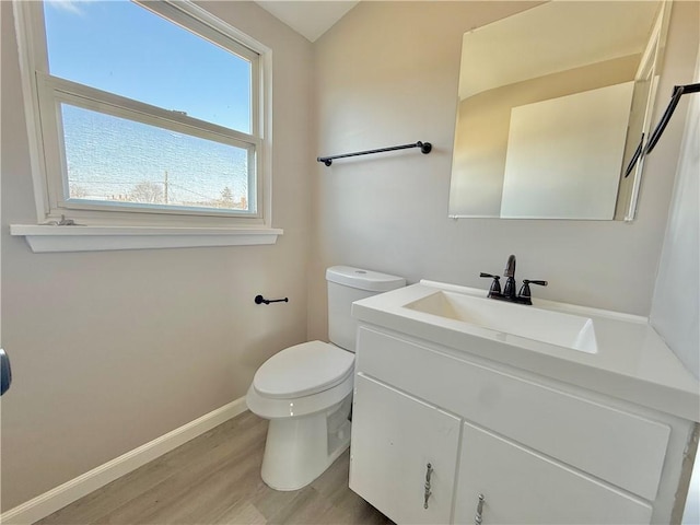 half bathroom featuring toilet, baseboards, wood finished floors, and vanity