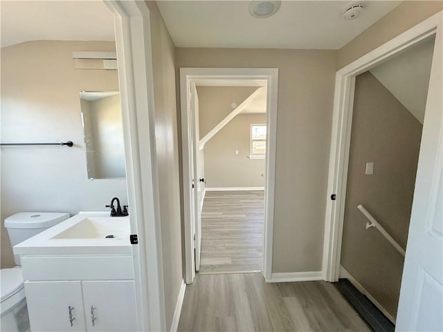 bathroom with toilet, vanity, baseboards, and wood finished floors