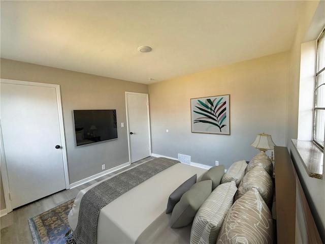 bedroom with visible vents, baseboards, and wood finished floors