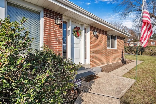 property entrance featuring brick siding and a lawn