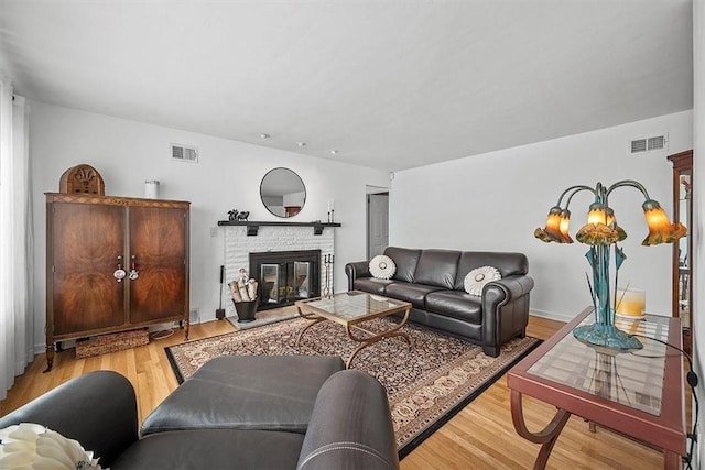 living room with a glass covered fireplace, visible vents, and wood finished floors