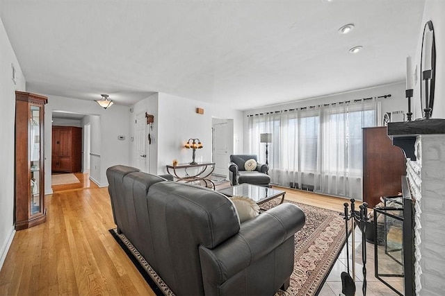 living room with light wood-type flooring, a fireplace, and baseboards