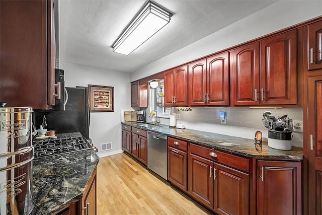 kitchen featuring visible vents, backsplash, dark brown cabinets, light wood-type flooring, and dishwasher