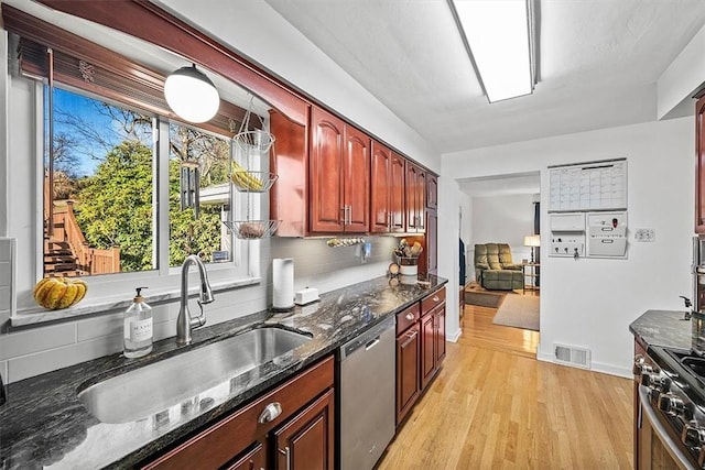 kitchen featuring reddish brown cabinets, visible vents, appliances with stainless steel finishes, light wood-style floors, and a sink