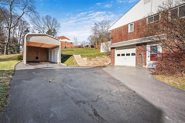 view of side of home featuring aphalt driveway, brick siding, a yard, a garage, and a carport