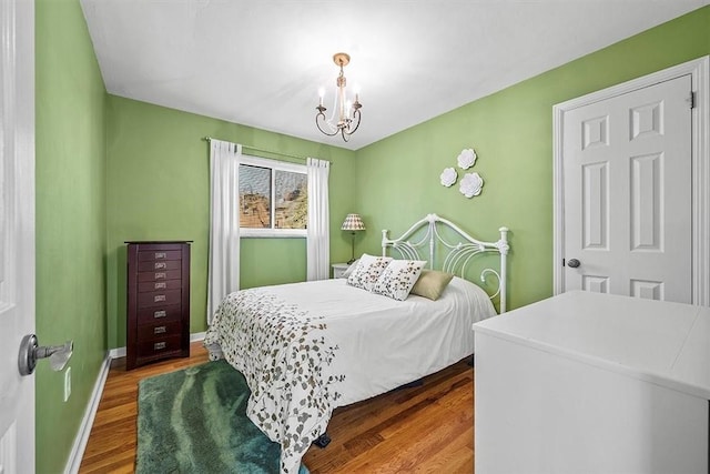 bedroom featuring a chandelier, wood finished floors, and baseboards