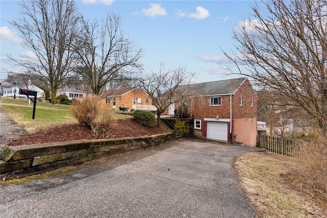 exterior space with driveway, a garage, fence, and brick siding