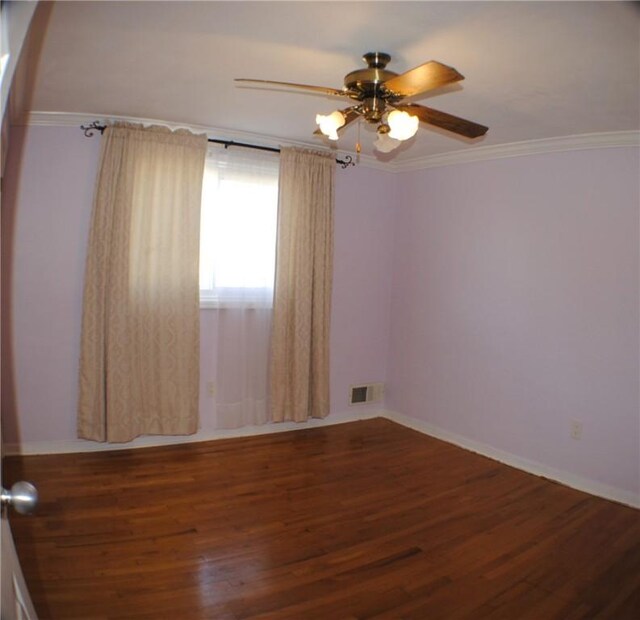 spare room with ceiling fan, visible vents, crown molding, and wood finished floors