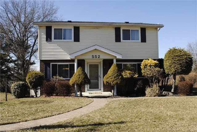 colonial home featuring a front yard and brick siding