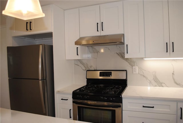 kitchen featuring light stone counters, under cabinet range hood, white cabinetry, appliances with stainless steel finishes, and backsplash