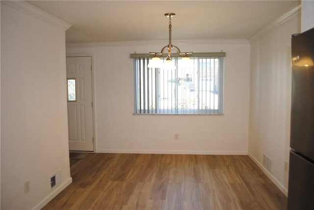 unfurnished dining area featuring visible vents, crown molding, baseboards, and wood finished floors