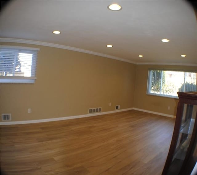 spare room with baseboards, crown molding, visible vents, and wood finished floors