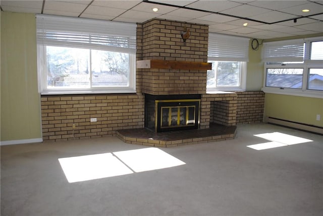 unfurnished living room with brick wall, a baseboard radiator, a paneled ceiling, and a brick fireplace