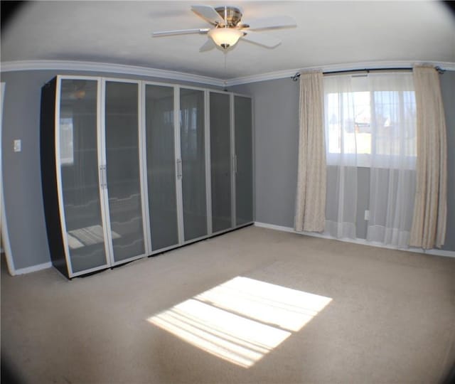 spare room with ornamental molding, carpet, ceiling fan, and baseboards