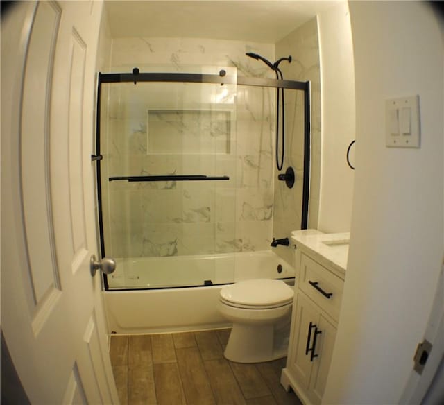 full bath featuring toilet, wood tiled floor, bath / shower combo with glass door, and vanity