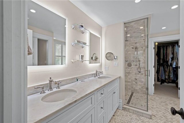 bathroom featuring double vanity, a stall shower, a sink, and a walk in closet