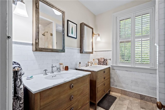 bathroom with a wainscoted wall, two vanities, a sink, and tile walls