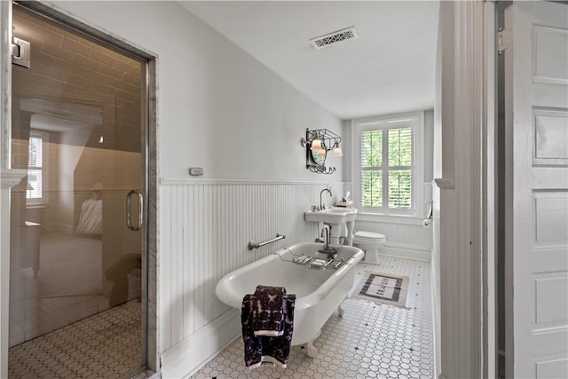 bathroom featuring a stall shower, visible vents, toilet, a wainscoted wall, and a freestanding bath