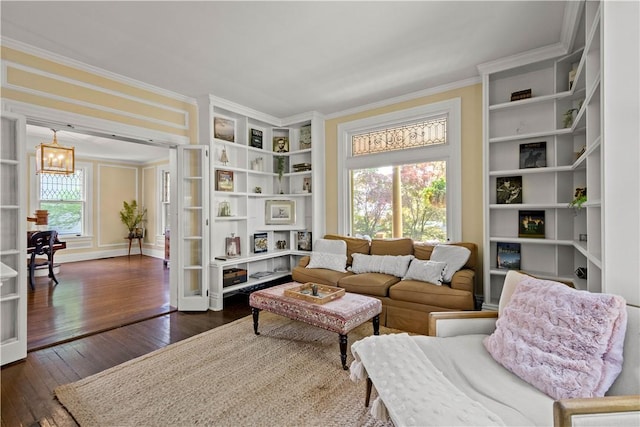 sitting room featuring a notable chandelier, built in shelves, ornamental molding, and dark wood-type flooring