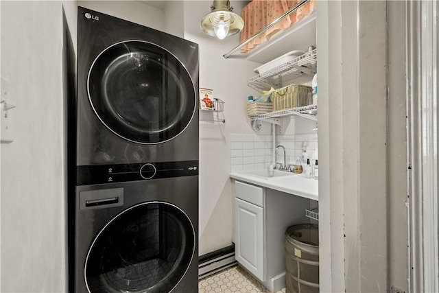 clothes washing area featuring stacked washer and clothes dryer, cabinet space, and a sink