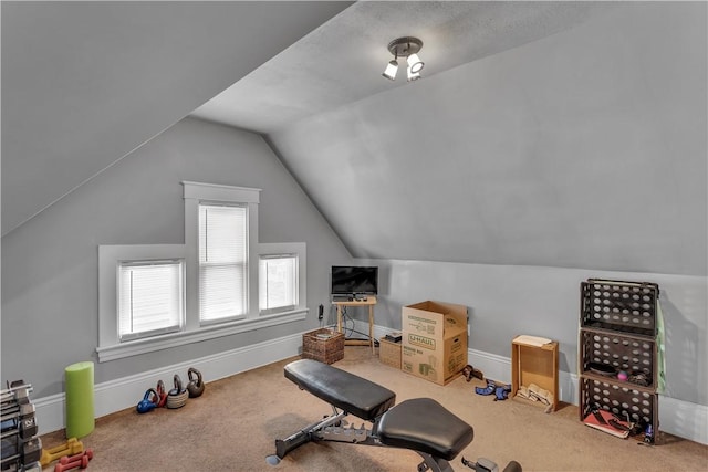 exercise room featuring carpet, baseboards, and vaulted ceiling