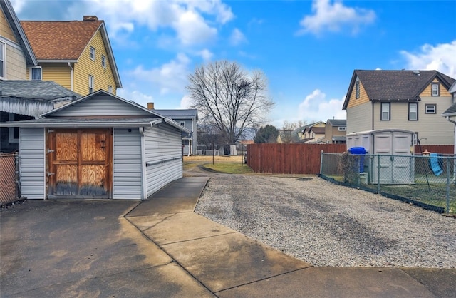 view of home's exterior with a storage unit, an outdoor structure, fence, and a residential view