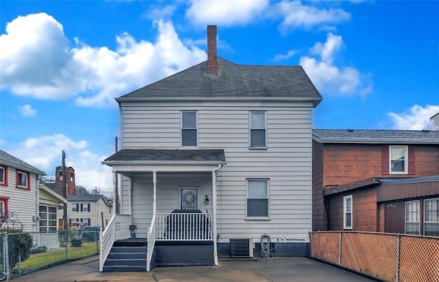 rear view of house with covered porch, a chimney, fence, and central air condition unit