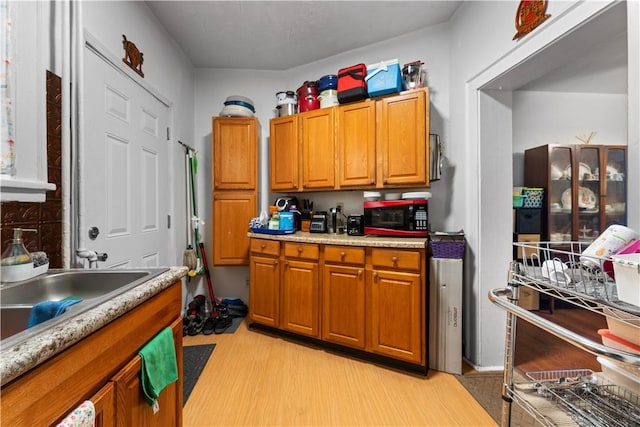 kitchen featuring light wood finished floors, brown cabinetry, and light countertops