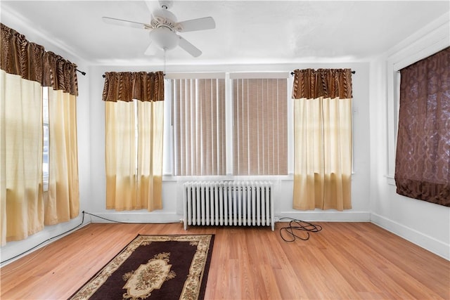 unfurnished sunroom featuring a ceiling fan and radiator