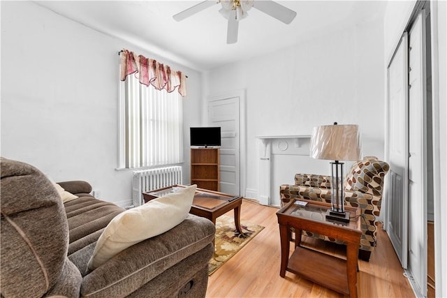 living room featuring a ceiling fan, light wood-type flooring, and radiator heating unit