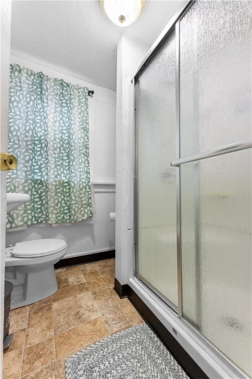 full bathroom featuring toilet, a stall shower, and stone finish floor