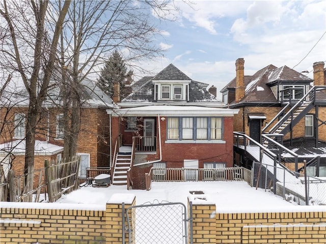 view of front facade featuring a fenced front yard, a gate, brick siding, and stairway