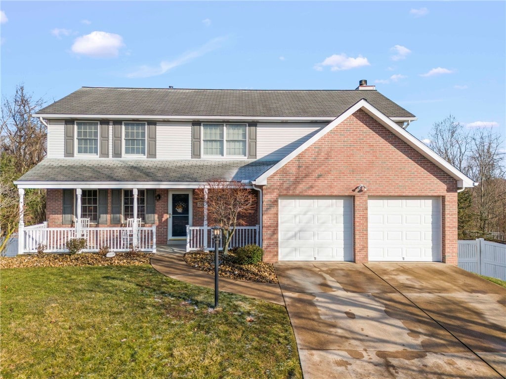 traditional-style house featuring brick siding, a porch, concrete driveway, a front yard, and a garage